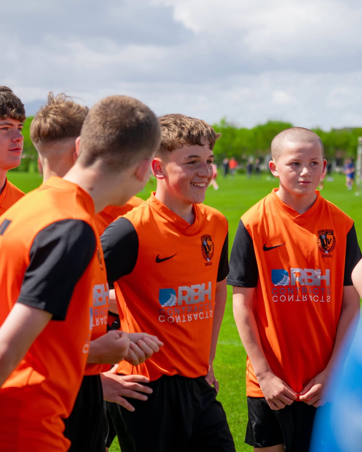 Youth football team in orange kits listening to their coach