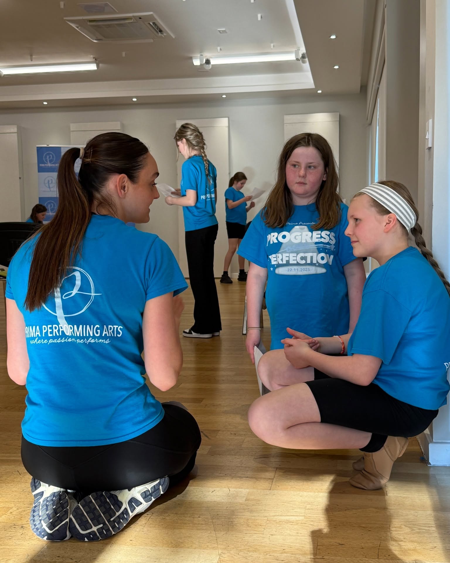Performing arts coach talking with two young dancers