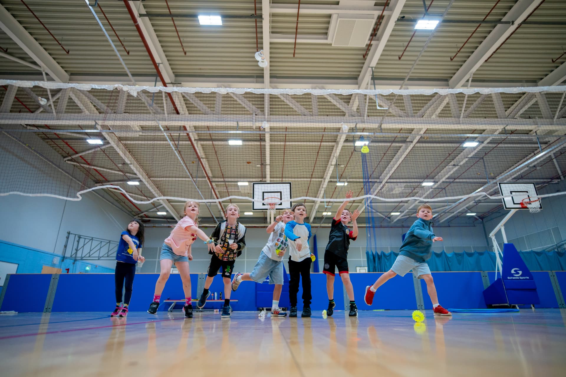Kids leaping for a shuttlecock during a badminton class